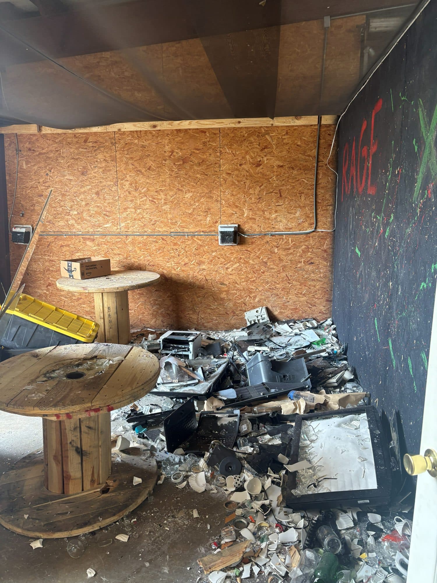 Rage room floor covered in broken glass and electronics before cleanup